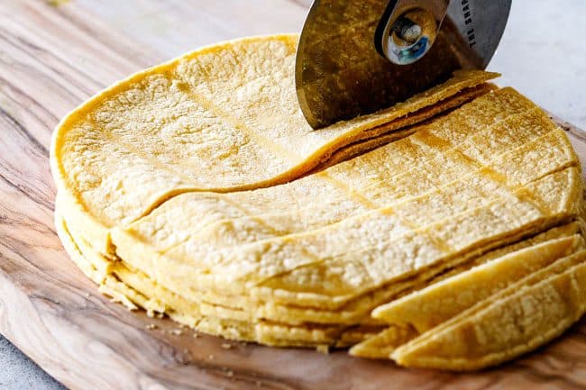 showing how to make Mexican Salad by  by cutting corn tortillas to make tortilla strips on a cutting board with a pizza cutter