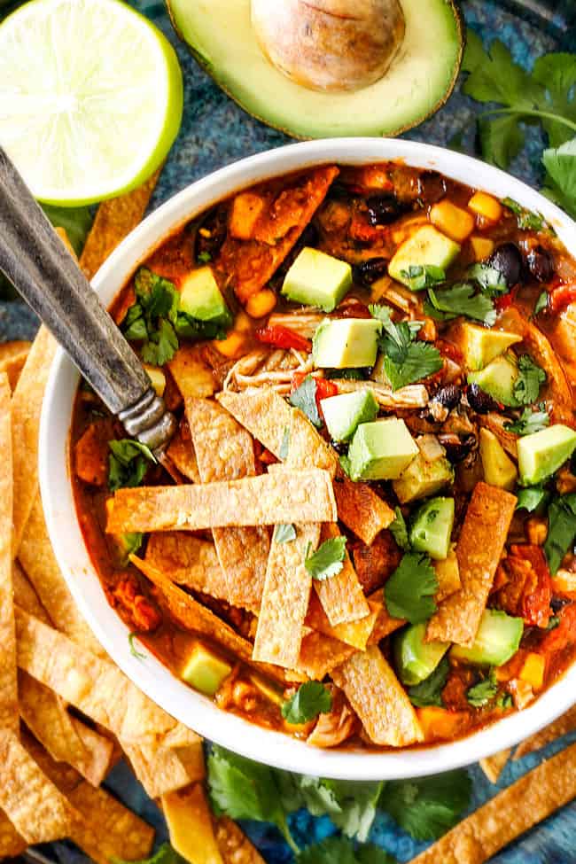 a white bowl of Mexican Chicken Tortilla Soup loaded homemade tortilla strips, avocados, sour dream