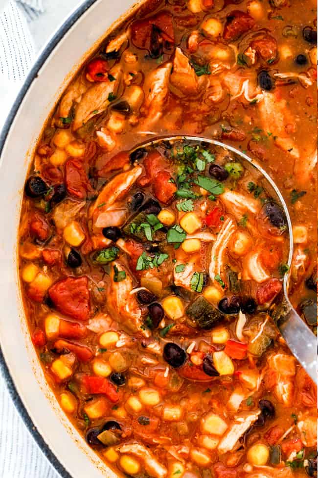 Showing how to make Crock Pot Chicken Tortilla Soup by putting chicken then tomatoes, green chiles, red bell peppers, poblano peppers, corn and black beans in the bottom of the crockpot