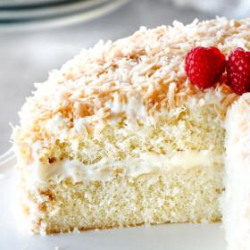 homemade Coconut Cake with a slice cut out looking at ceneter of cake with cream