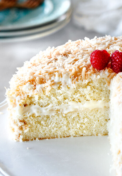 homemade Coconut Cake with a slice cut out looking at ceneter of cake with cream