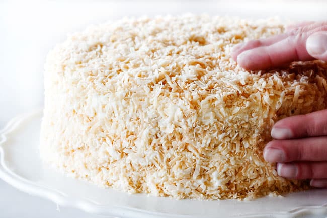 How to Make Coconut Cake by patting toasted coconut into coconut cake