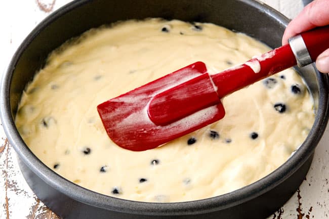 Showing how to make Lemon Blueberry Cake with Lemon Curd by smoothing batter in cake pan