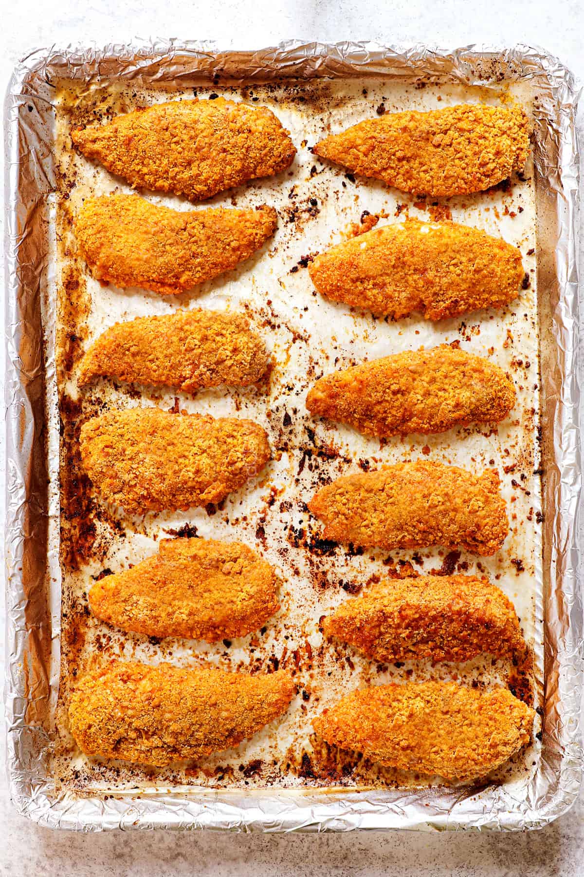 showing how to make oven fried chicken by baking the chicken on a baking sheet until crispy