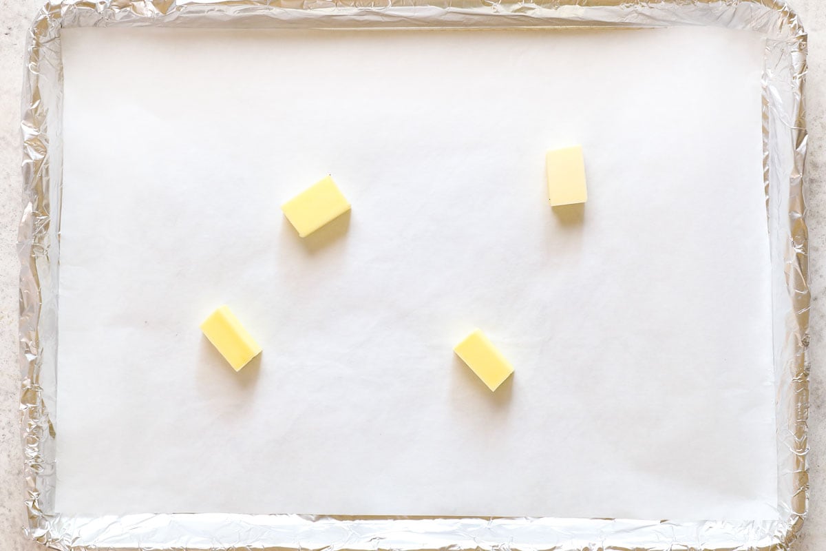 showing how to make oven fried chicken by melting the butter on the baking sheet in the oven