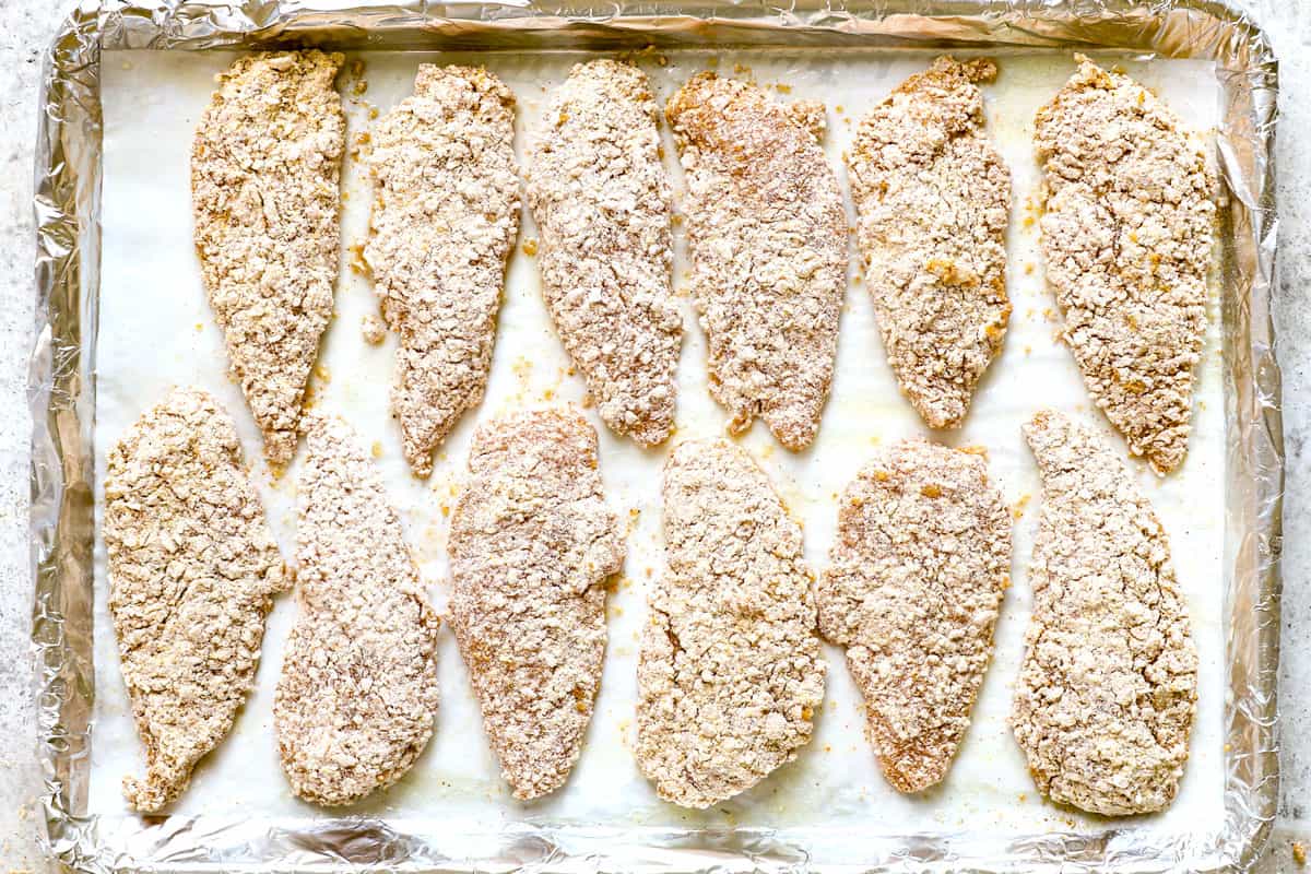 showing how to make oven fried chicken by lining the chicken on the buttered baking sheet