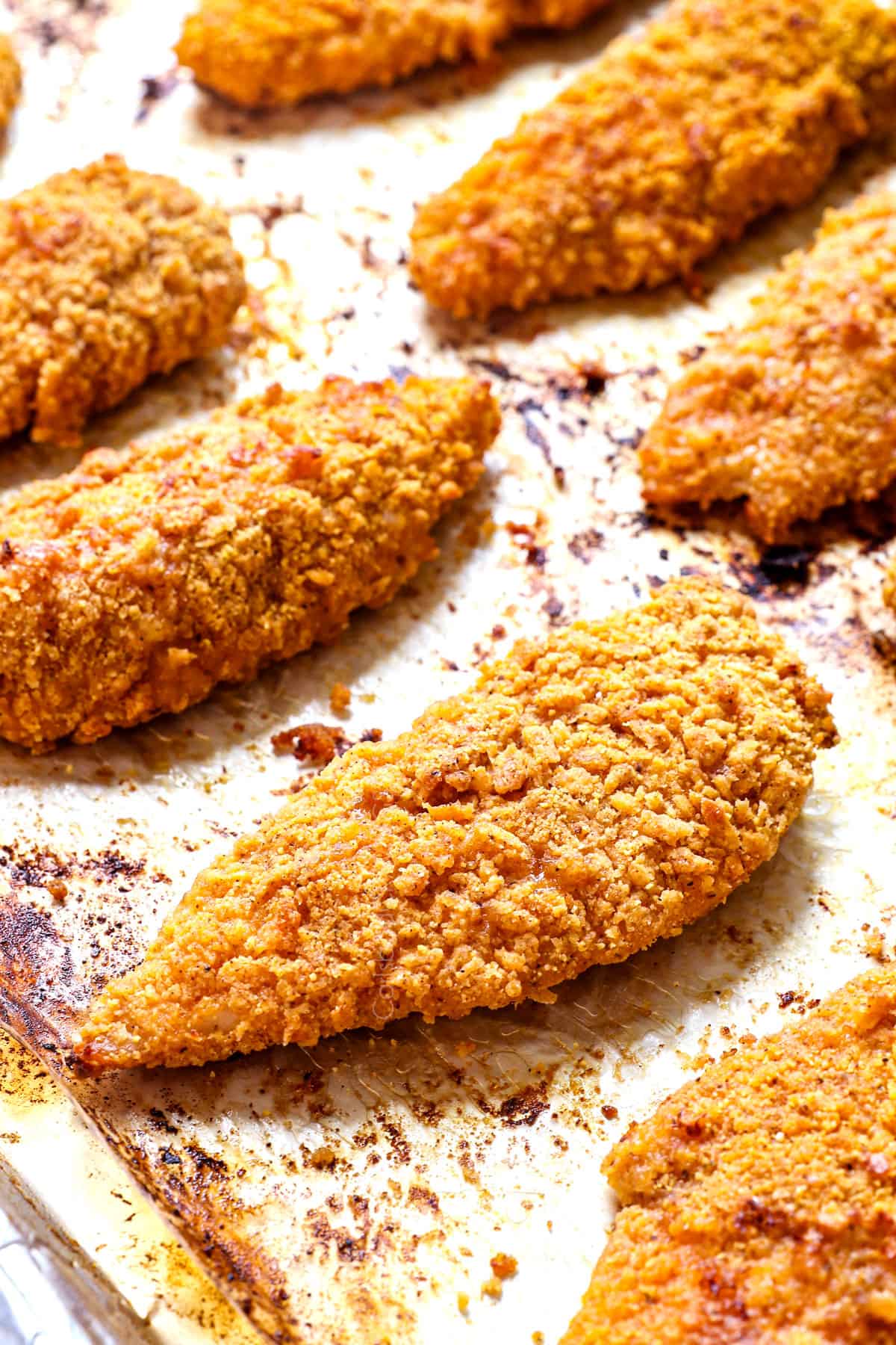 up close of baked breaded chicken on a baking sheet showing how crispy it is