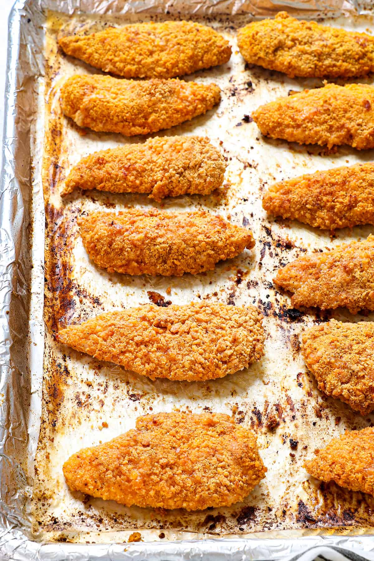 baked breaded chicken lined on a baking sheet showing how crispy it is