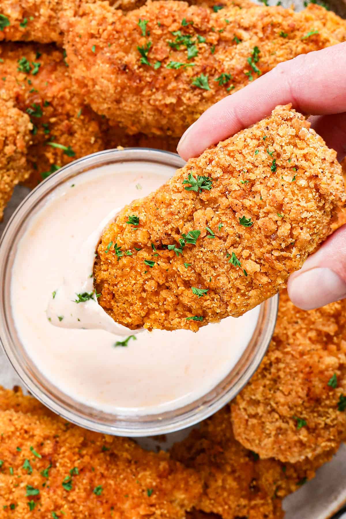 showing how to serve oven fried chicken recipe by dipping it into ranch