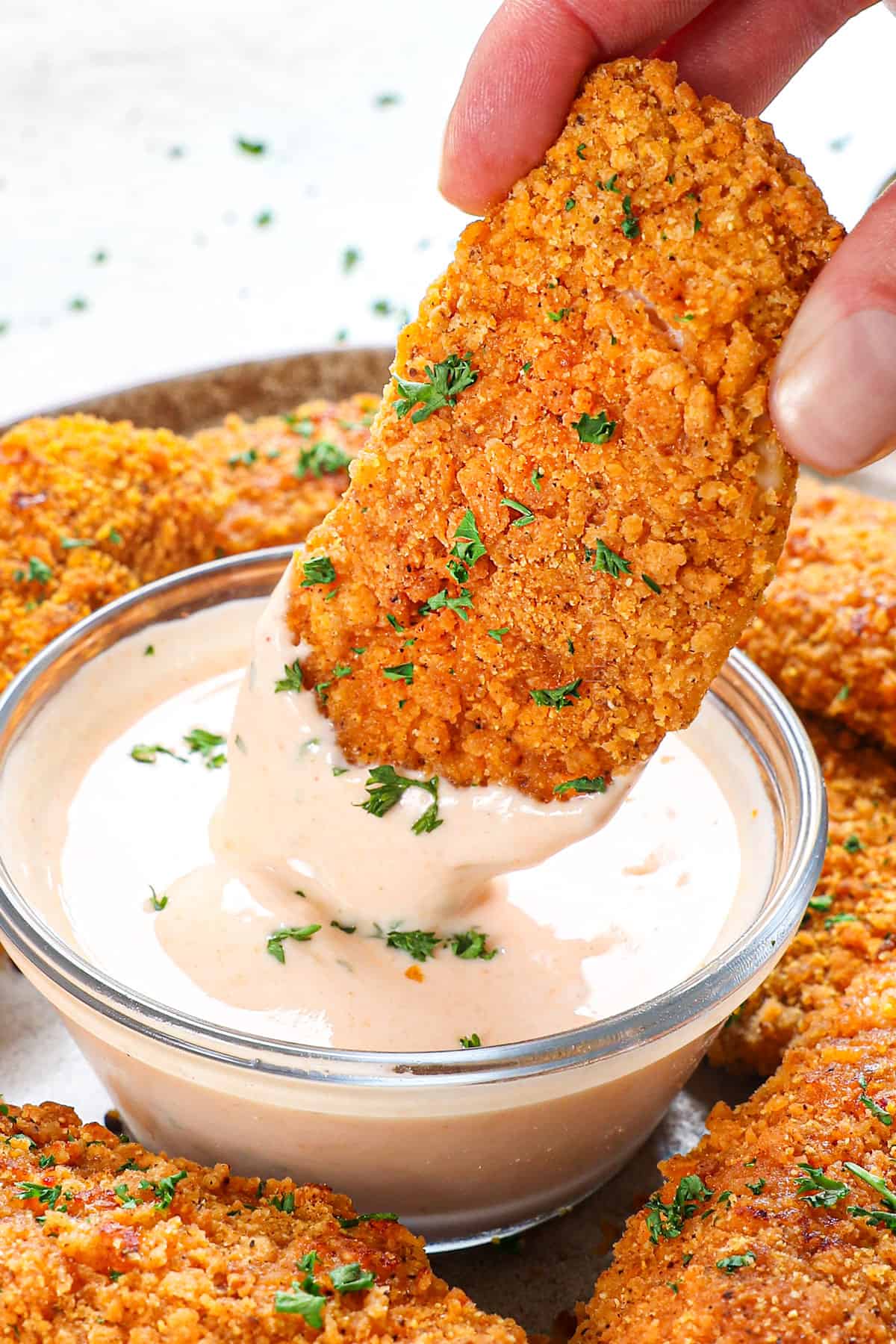 showing how to serve oven fried chicken recipe by dipping it into ranch