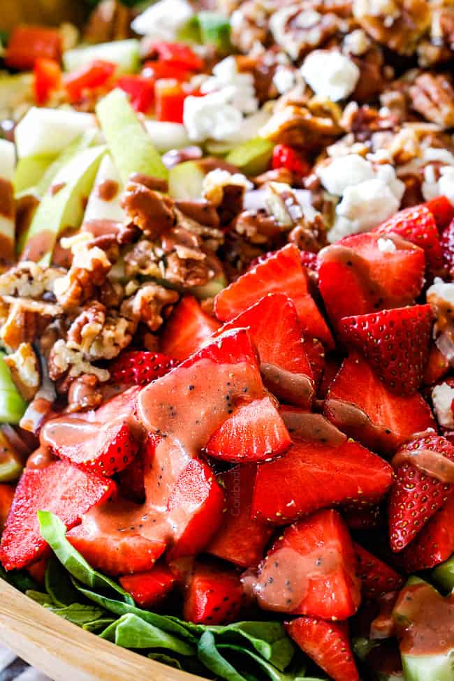 up close shot of Strawberry Spinach Salad with strawberry balsamic vinaigrette, caramelized pecans and goat cheese in a wood bowl