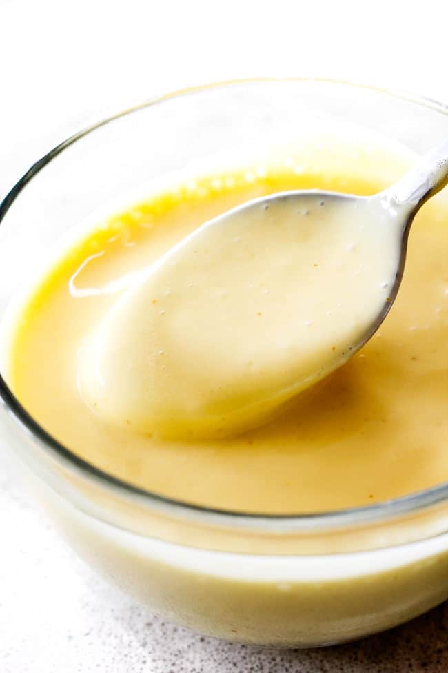Blender Hollandaise Sauce in a glass bowl with spoon showing how rich and creamy it is