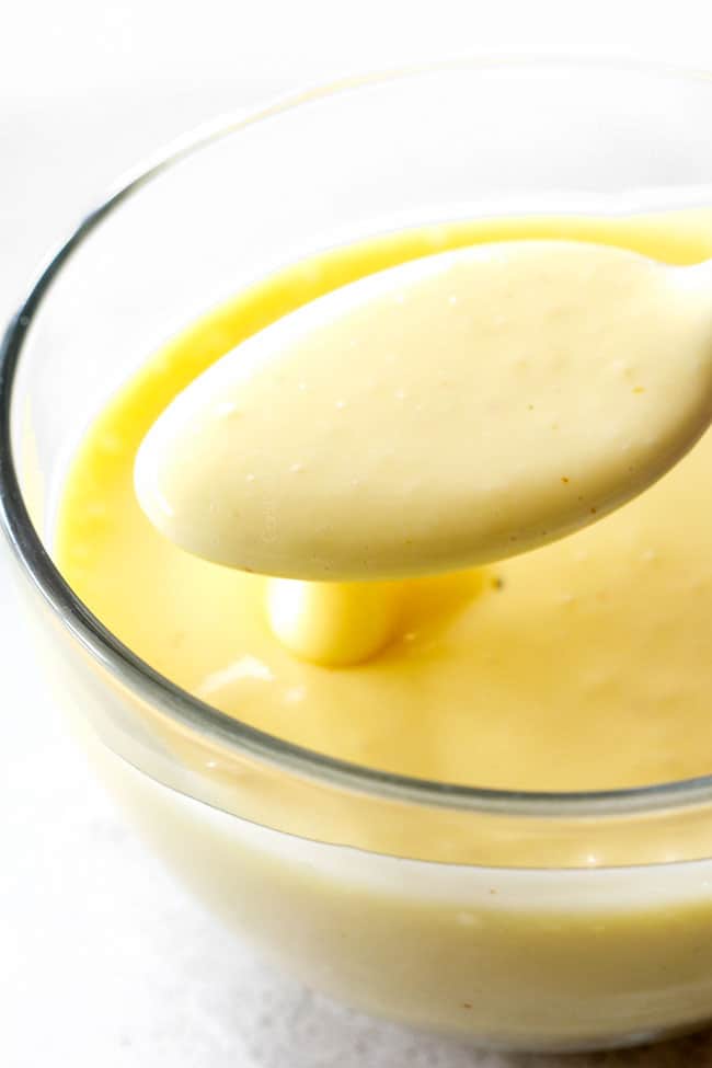 Blender Hollandaise Sauce in a glass bowl with spoon showing how rich and creamy it is