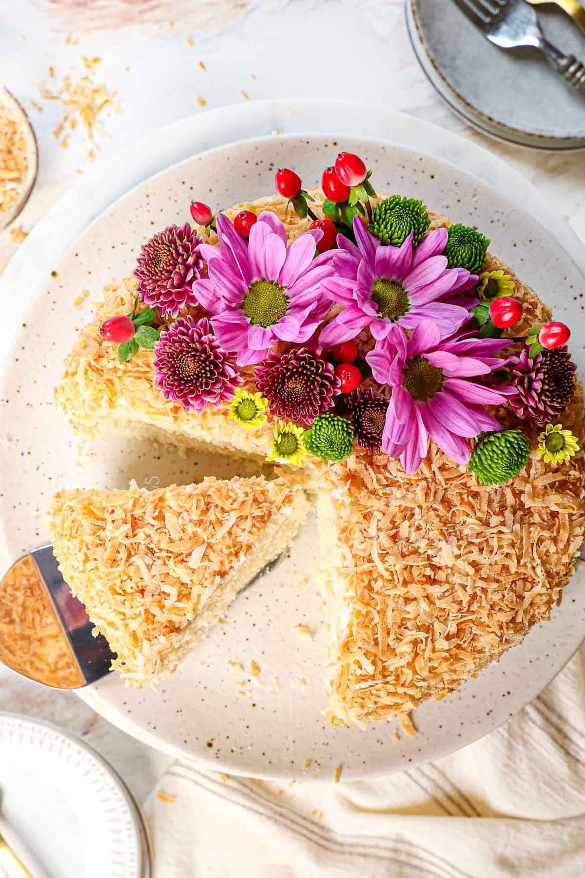 top view of coconut cake recipe coated in toasted coconut flakes on a cake stand