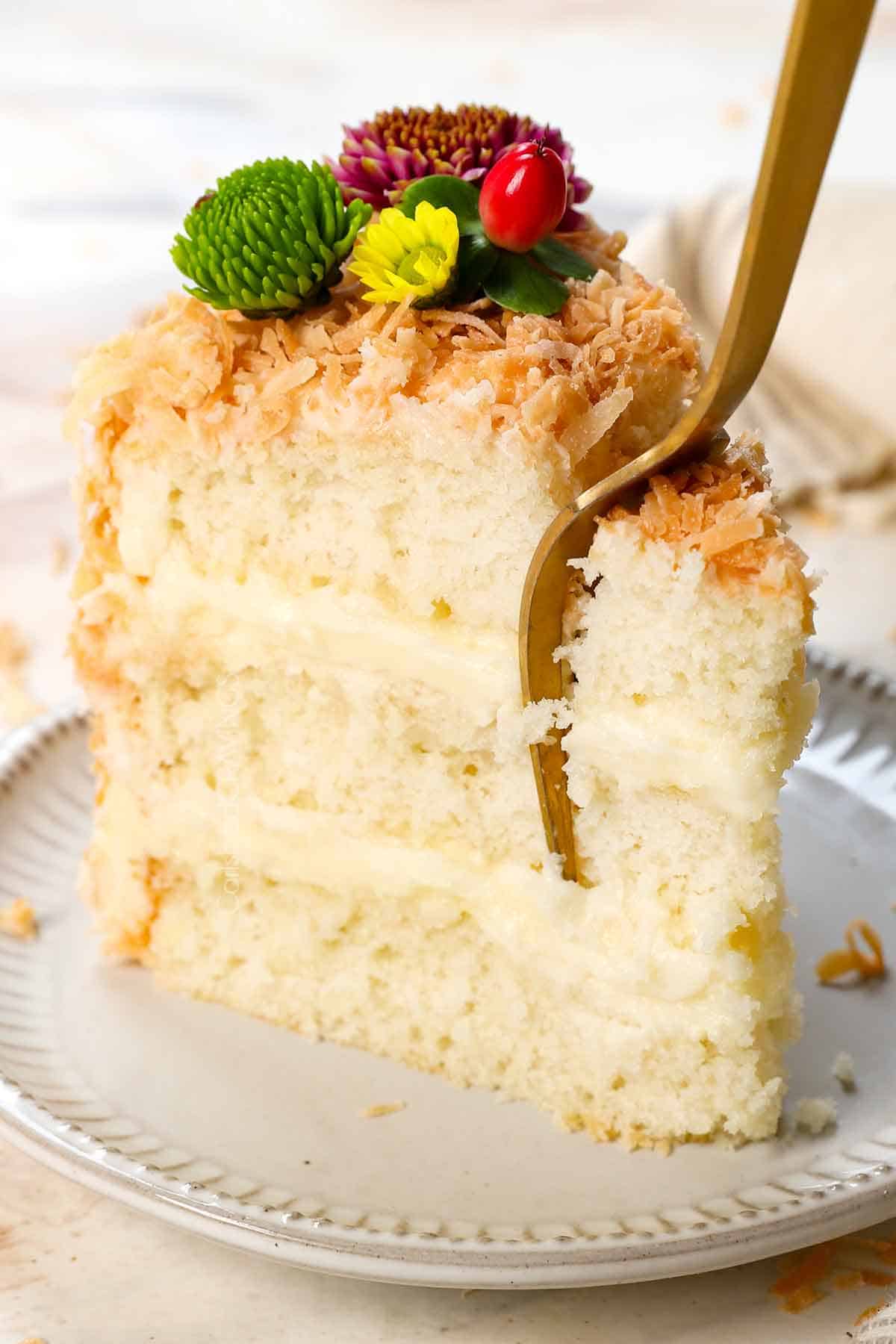 taking a bite of coconut coconut cake with a fork showing how soft and fluffy it is