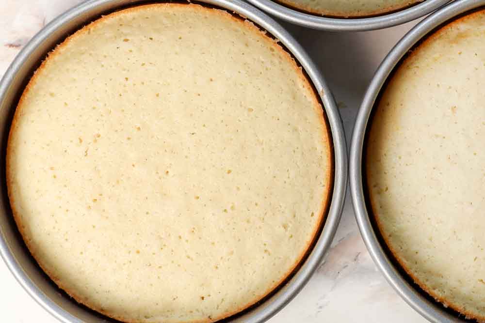 showing how to make coconut cake by baking the cakes, then cooling on a wire rack