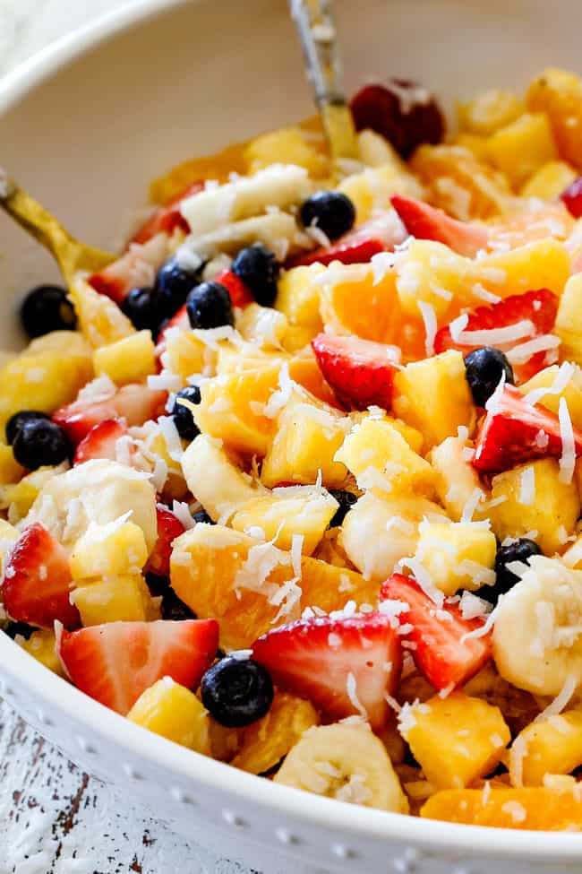 side view of best Pina Colada Fruit Salad with pineapple, coconut, mandarin oranges, strawberries and blueberries in a white bowl