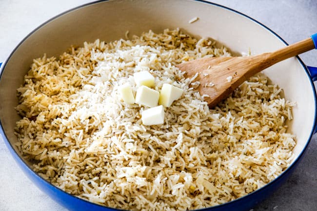 Showing how to prepare Lemon Rice by stirring in butter into cooked rice in a blue pot