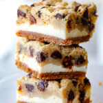 stack of cookie dough cheesecake bars with graham cracker crust, cheesecake and cookie dough
