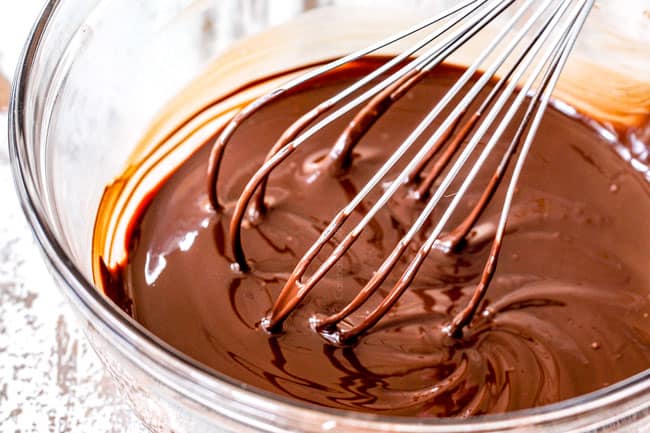 melted chocolate in a glass bowl being whisked showing How to Make Chocolate Covered Strawberries