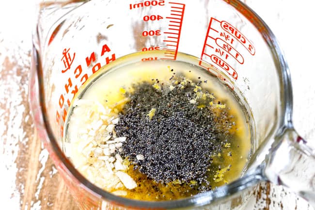 Whisking together oil, apple cider vinegar, poppy seeds, minced onions in a measuring glass to make Poppy Seed Dressing for pasta salad