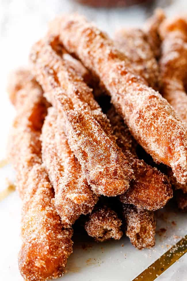 up close of authentic Spanish churros in a stack on a white marble cutting board