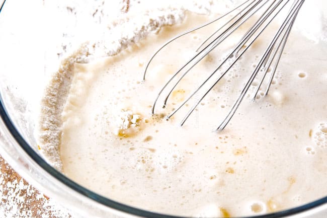 whisking together flour, oil, sugar and water in a glass bowl Showing how to make churro batter