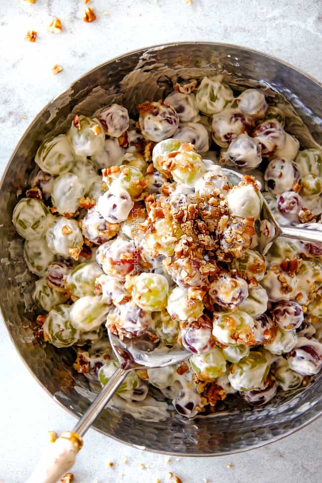 top shot of creamy grape salad in a metal bowl with chopped toasted pecans