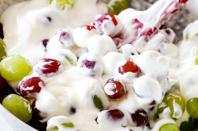 mixing grapes with cream cheese yogurt dressing showing how to make easy grape salad