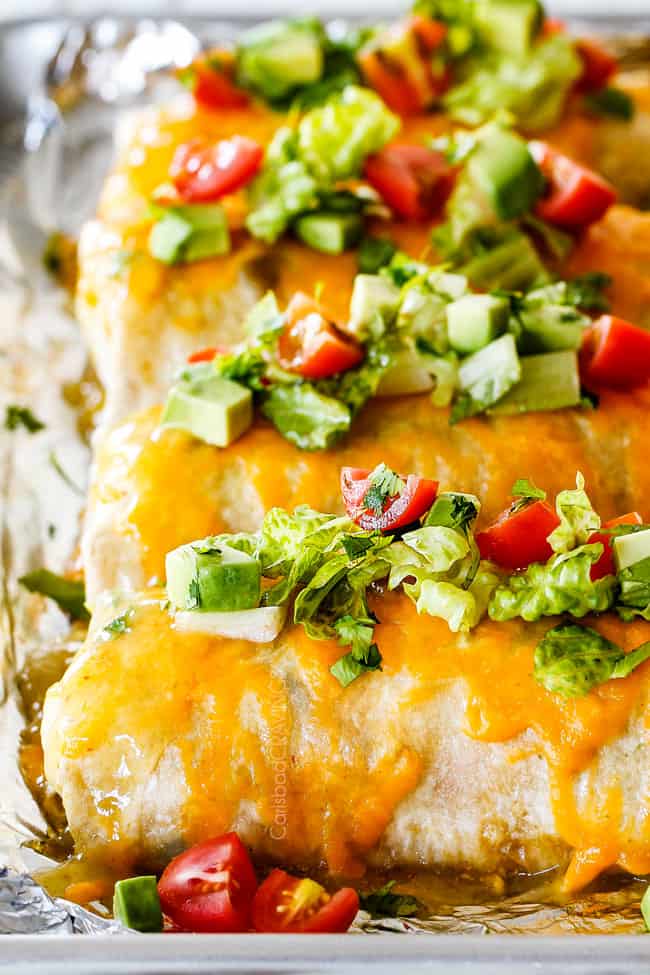 Baking sheet of Wet Burritos garnished with lettuce and tomatoes