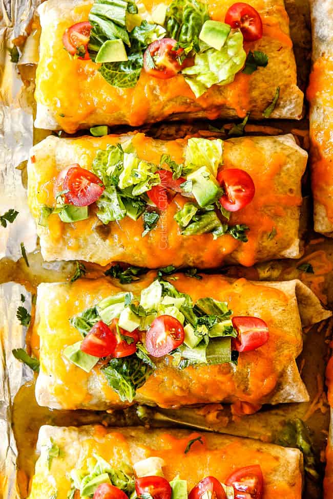 top view of Baking sheet of Wet Burritos garnished with lettuce and tomatoes