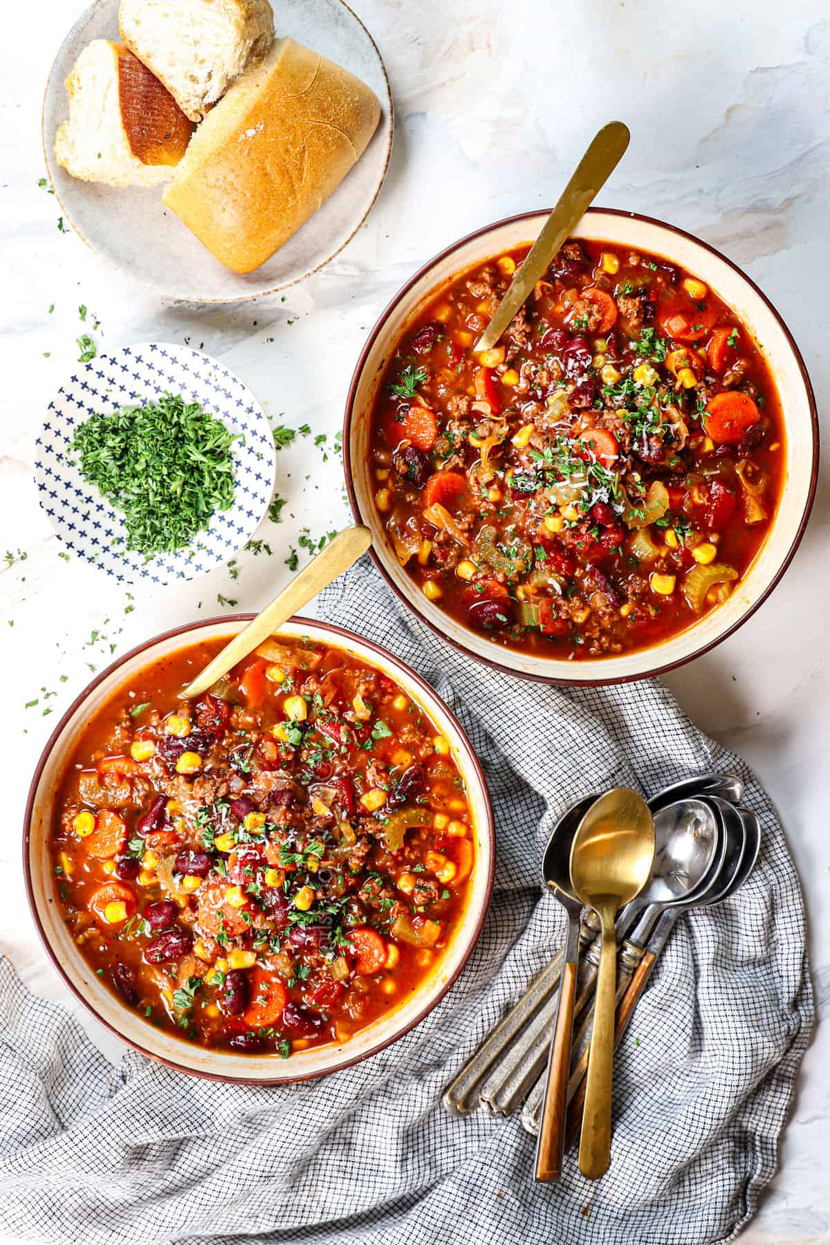 top view of two bowls of beef vegetable soup recipe showing how to serve with fresh parsley and fresh Parmesan