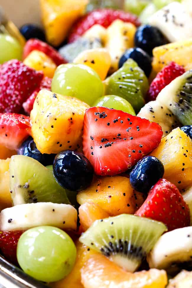 up close of fresh fruit salad in bowl with pineapple, strawberries, blueberries, bananas, kiwis, grapes and oranges