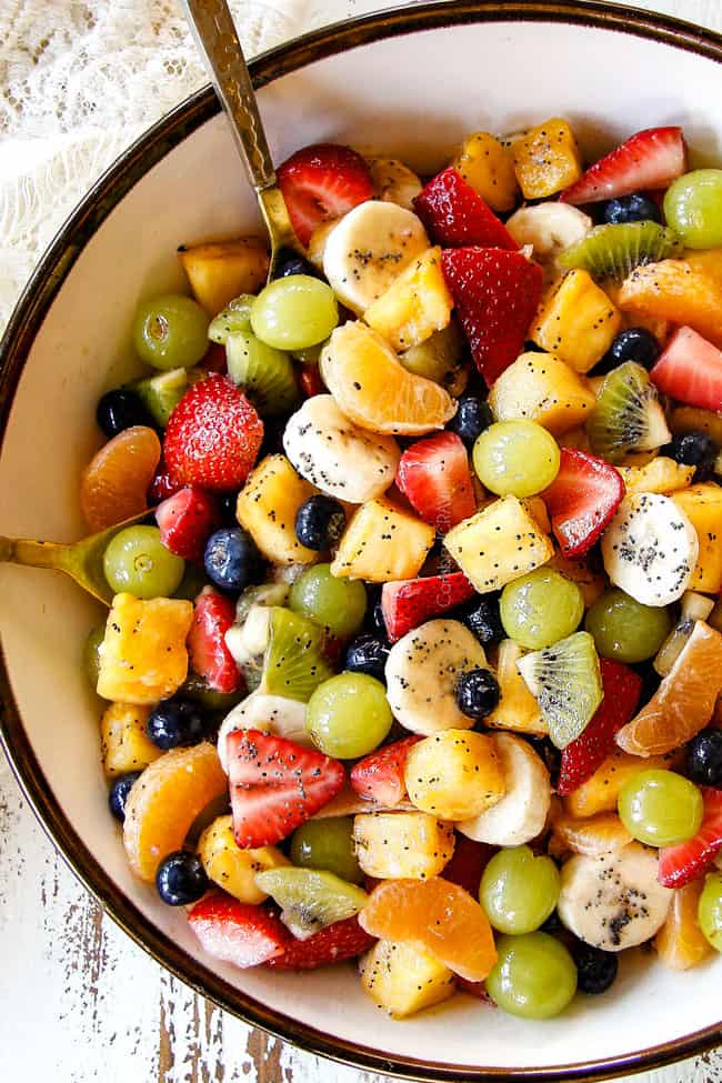 top view of best fruit salad in bowl with pineapple, strawberries, blueberries, bananas, kiwis, grapes and oranges
