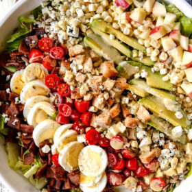 top view of Cobb salad with lettuce, hard boiled eggs, avocados, bacon, tomatoes and blue cheese