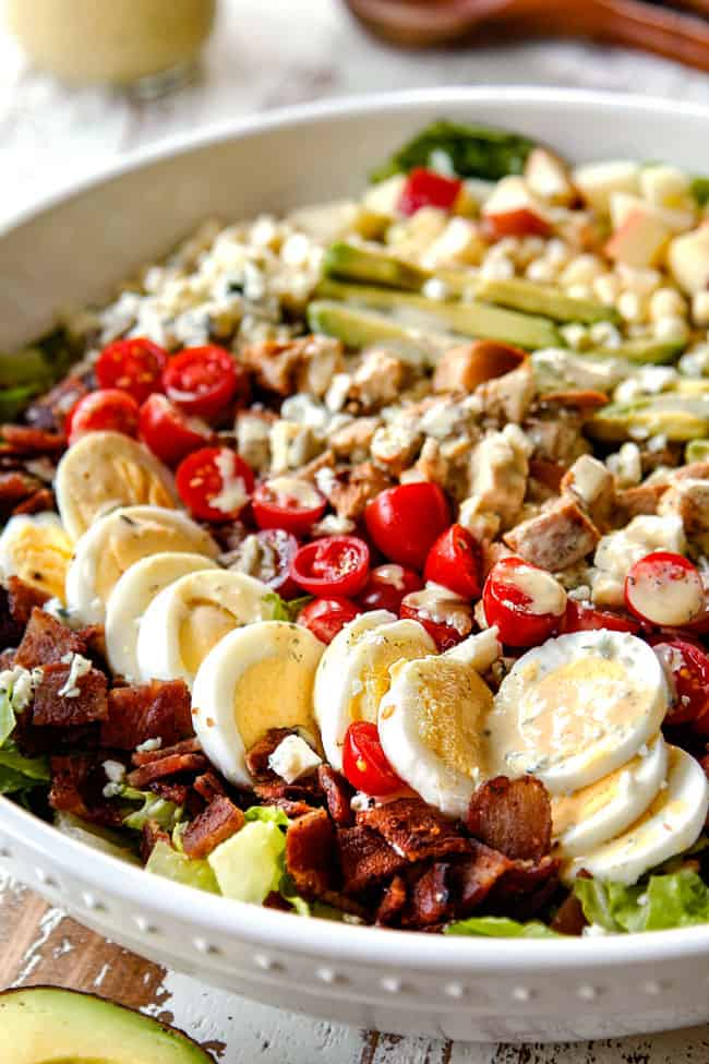 up close side view of Cobb salad with lettuce, hard boiled eggs, avocados, bacon, tomatoes and blue cheese