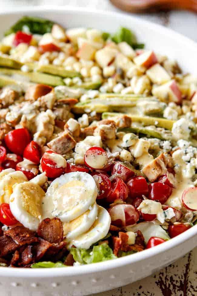 up close side view of Cobb salad with lettuce, hard boiled eggs, avocados, bacon, tomatoes and blue cheese