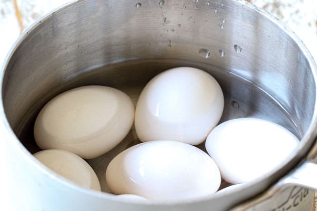 showing how to make cobb salad by cooking hard boiled eggs in a saucepan