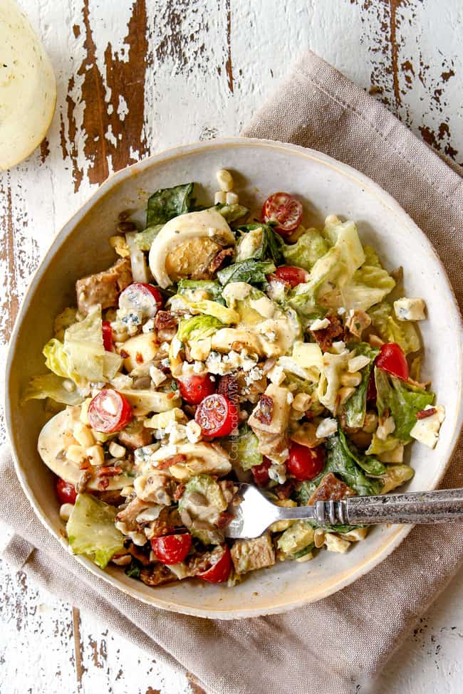 top view of Cobb Salad on a plate with avocado, eggs, bacon, tomatoes, lettuce and blue cheese