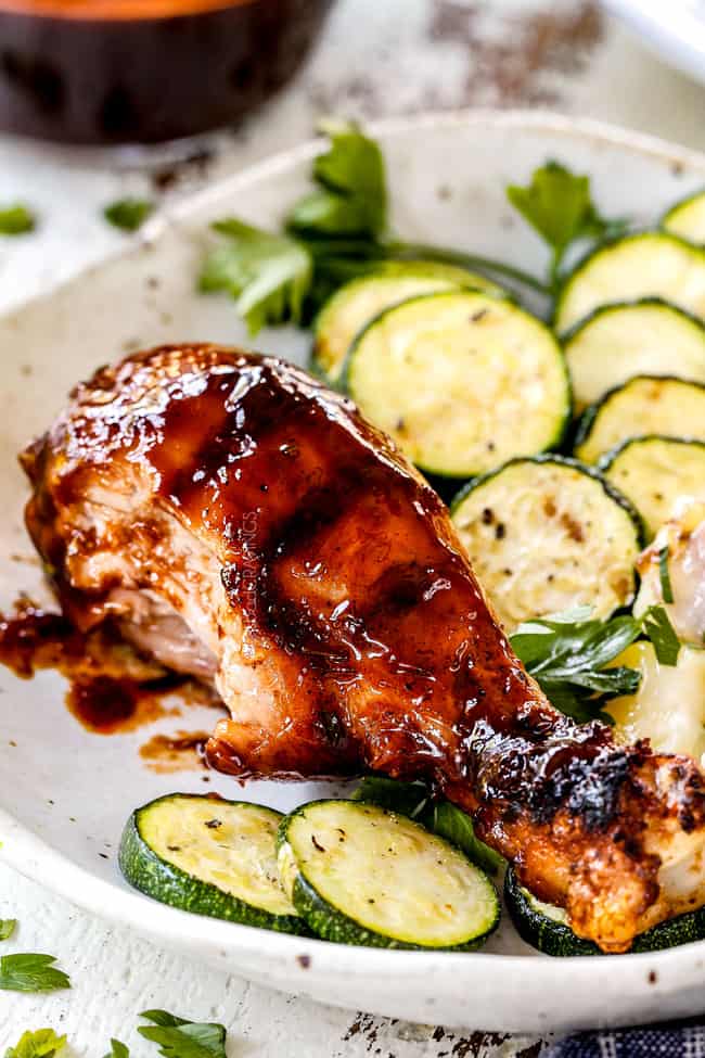 easy grilled bbq chicken with a bite taken out of the chicken drumstick on a plate with zucchini