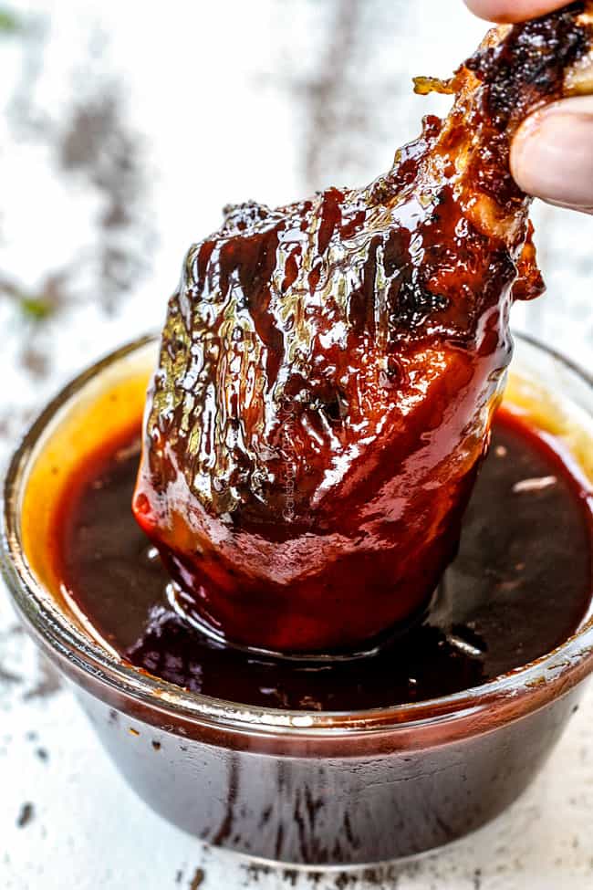 dipping grilled bbq chicken in homemade barbecue sauce