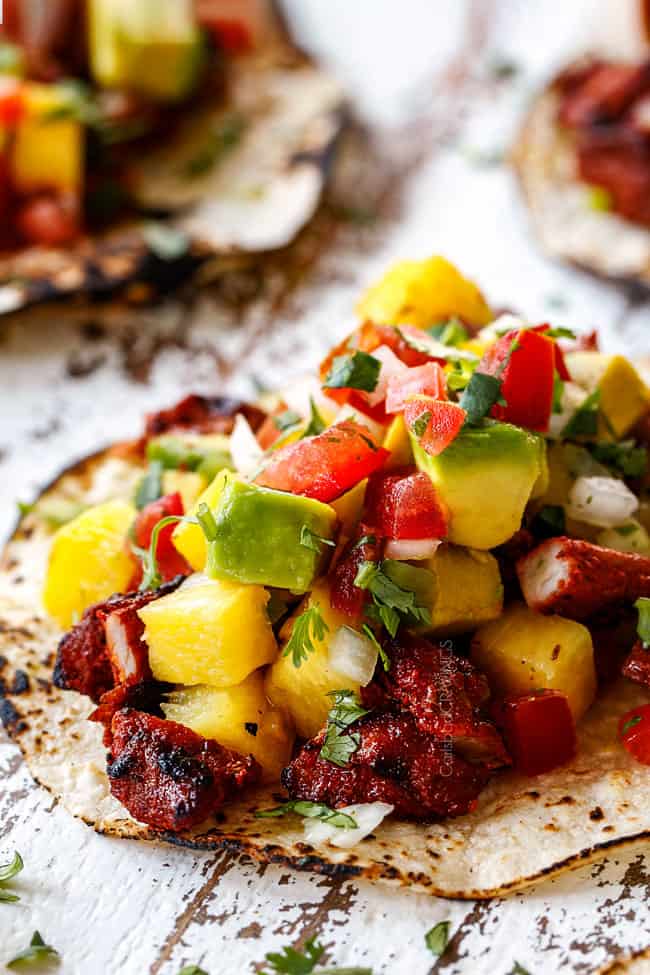 up close of best Tacos Al Pator with pineapple, pico de gallo and avocado on a white board