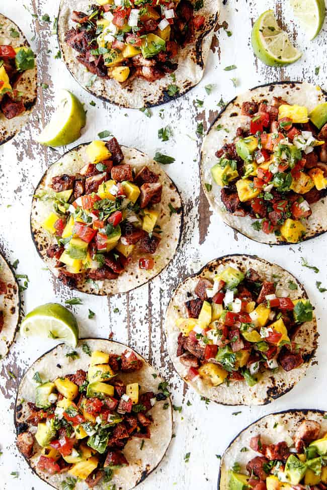 top view of 5 best Tacos Al Pator with pineapple, pico de gallo and avocado on a white board