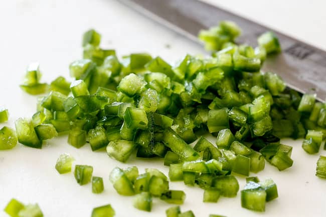 chopping jalapenos on a white cutting board for easy pico de gallo