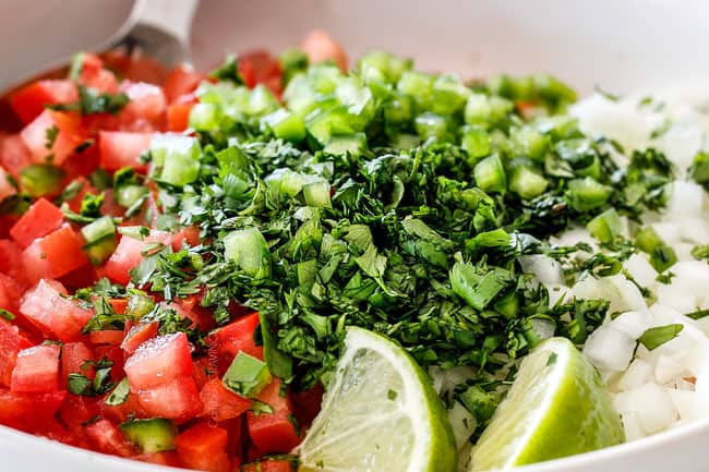 up close of tomatoes, cilantro, onions, jalapenos, lime juice in a white bowl for the best pico de gallo recipe