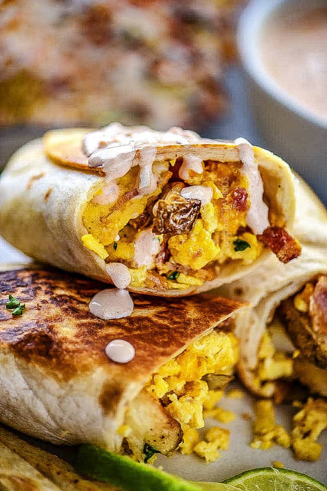 up close of a breakfast burrito drizzled with sauce 