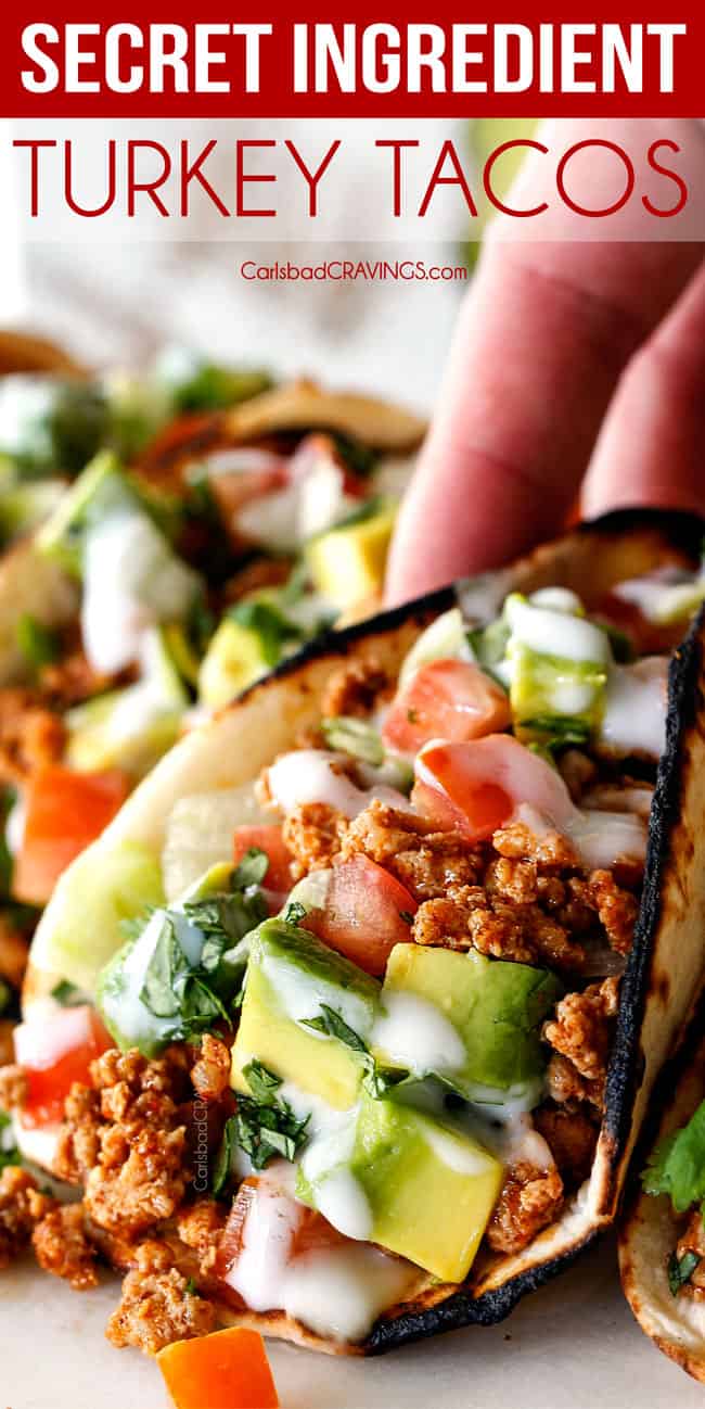 up close of picking up a healthy turkey taco with ground turkey, taco seasoning, lettuce, sour cream, tomatoes and avocados