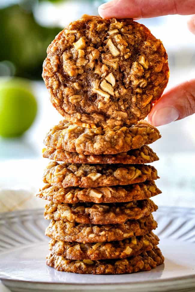 a stack of apple cookies on a white plate holding up one apple oatmeal cookie