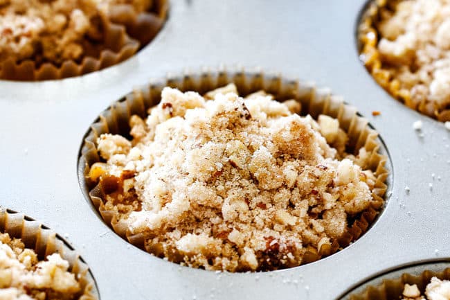 showing how to make fresh pumpkin muffins by adding crumb topping to muffin batter