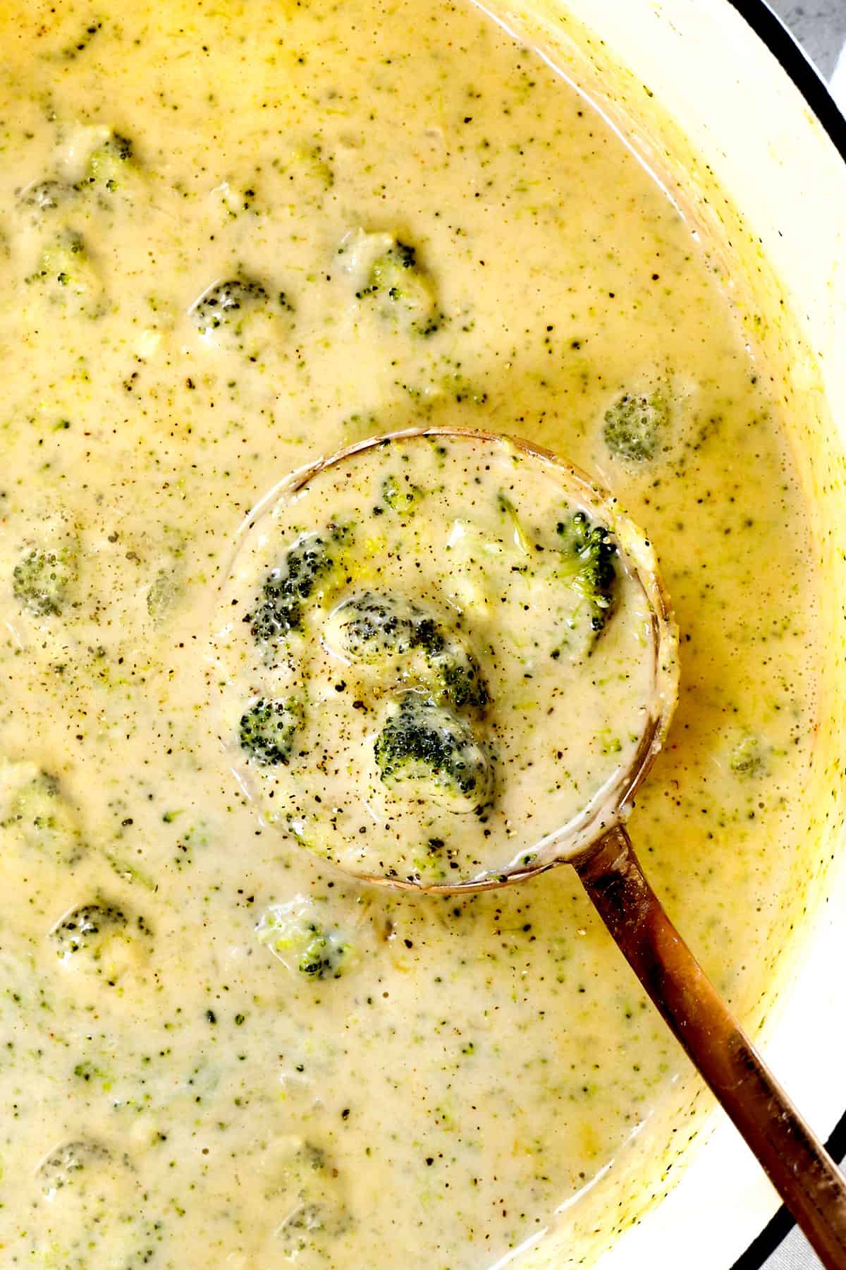 top view of cheesy broccoli soup in the pot showing the thick, creamy consistency with bits of broccoli florets